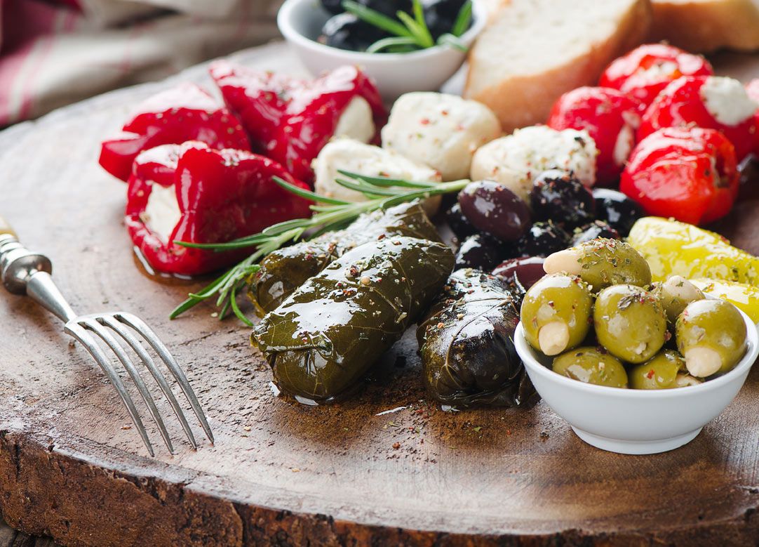 Тарелка с оливками, перцем и другими овощами, привлекательно оформленная.