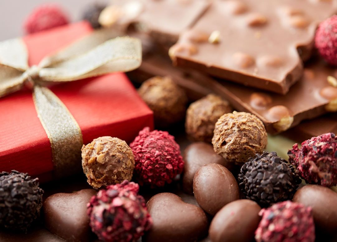 Шоколад и ягоды, украшенные красной лентой, на белой тарелке.